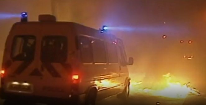 A screenshot from a video of a police van driving towards fire during the riots (Picture: BBC)